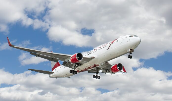 Photo by John McArthur white and red flying airplane under white clouds