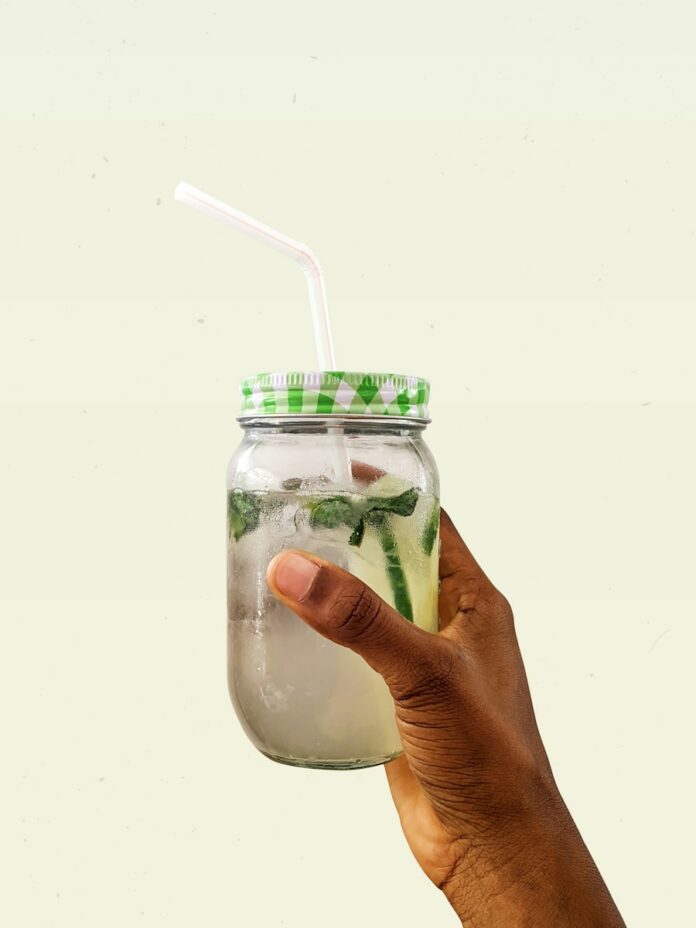 Photo by Emmanuel Ben-Paul person holding clear glass jar with green and white lid