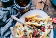 운동 전후에 좋은 음식과 피해야 할 음식 bacon strips and melted cheese topped fries on oval white and blue platter with gray stainless steel forks